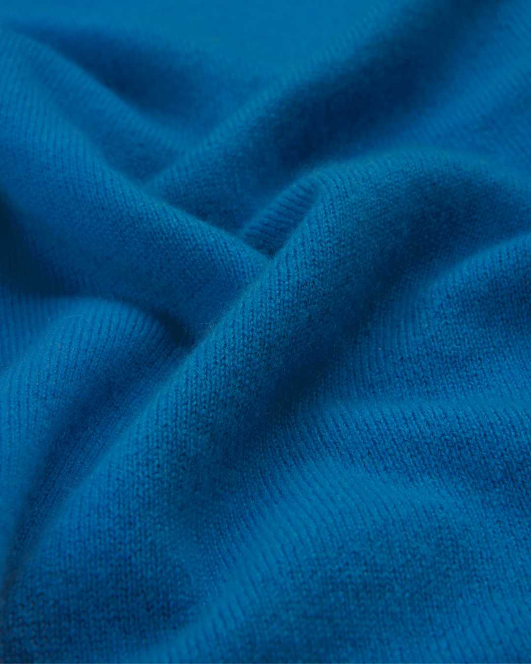 Close-up image of a blue cashmere sweater jumper, showing the texture and fabric.