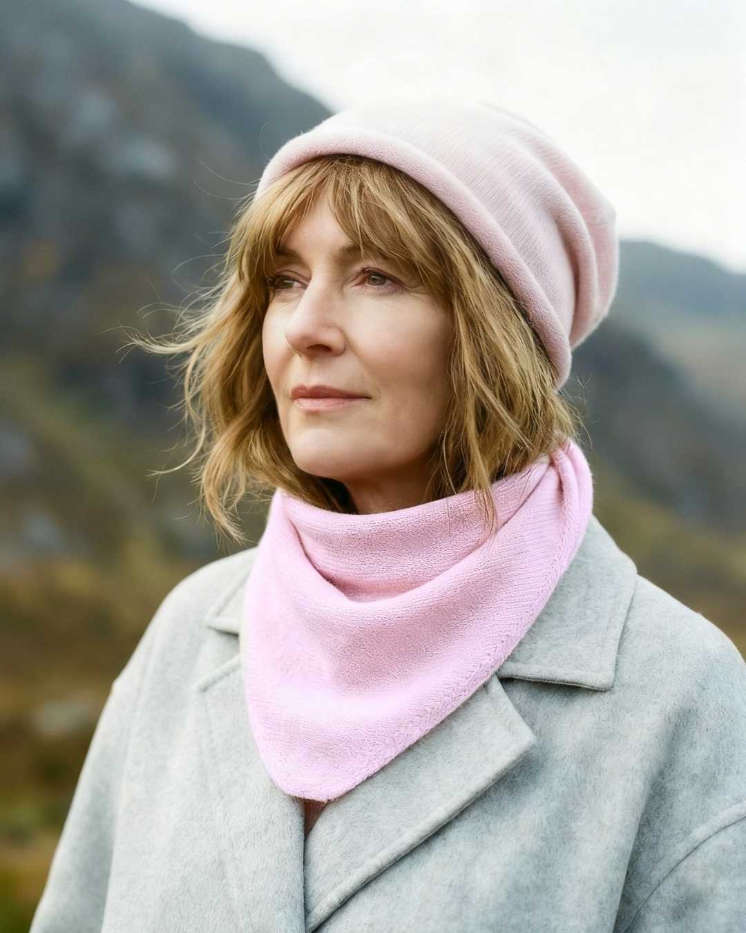 irish woman wearing a pure cashmere pink neck scarf with a grey coat in the moutains