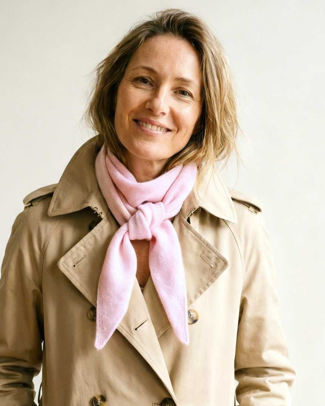 Woman wearing a beige trench coat and pink scarf from WEAR WITH Cashmere