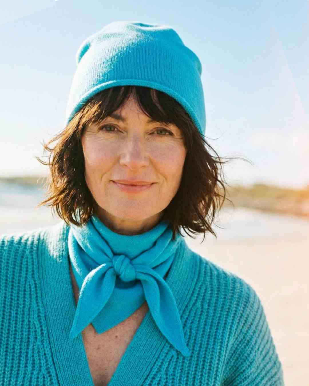 Irish woman on a beach wearing a turquoise hat and neck scarf