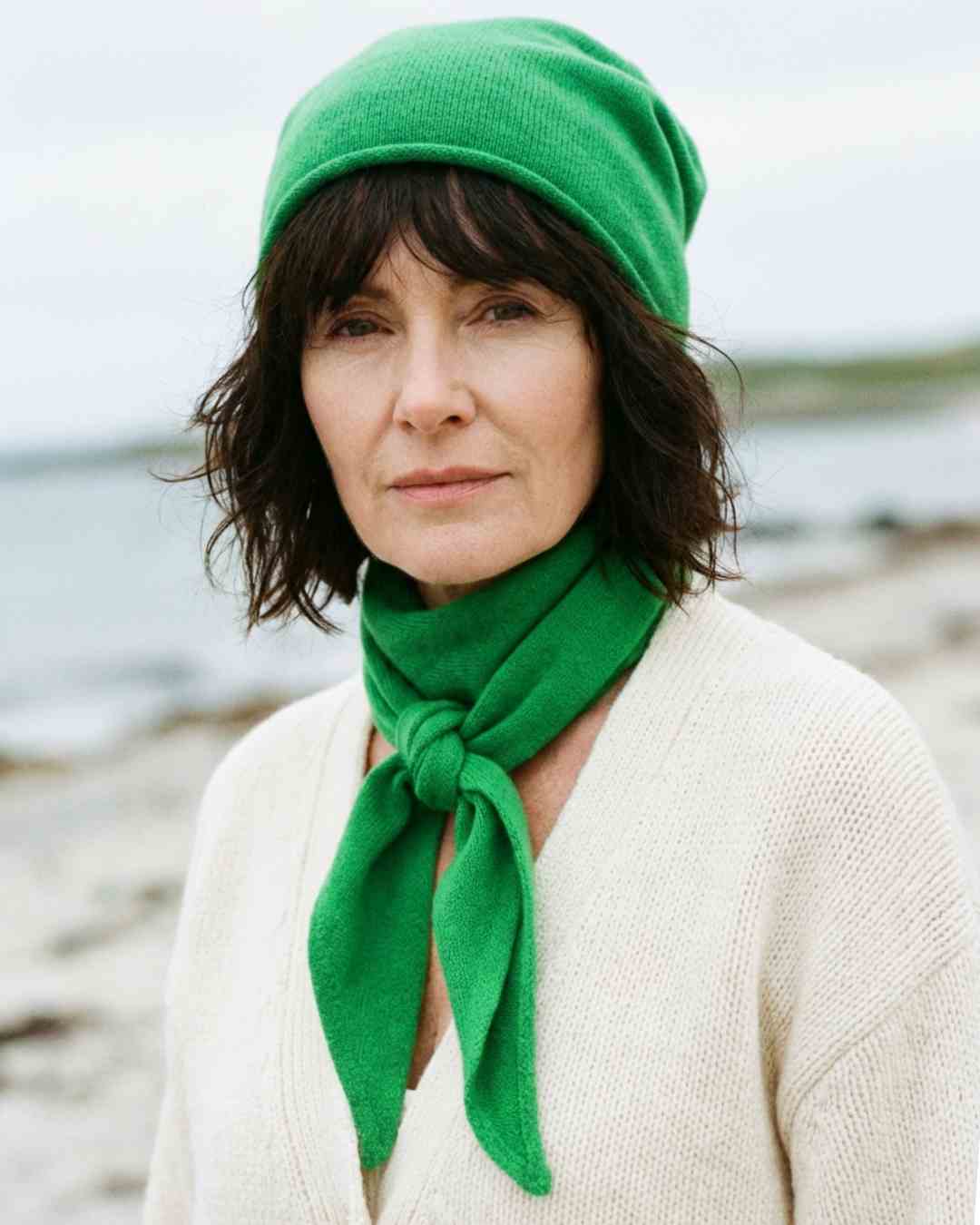 Irish woman on a beach wearing green cashmere beanie and scarf sustainable style