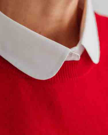 Close-up of a person wearing a christmas red cashmere sweater with a contrasting white faux shirt collar.